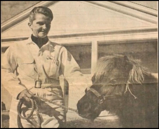 Vintage black-and-white photo of a woman holding the lead rope of a small pony
